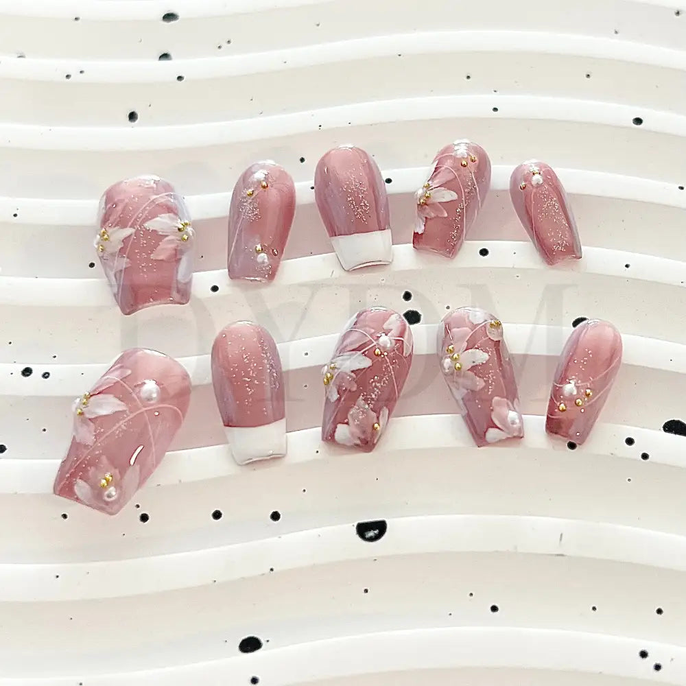 Blooming Fantasy Handmade press-on nails in pink, with classic French tip, white flowers, charming pearl accents, and glitters for an elegant and charming look.