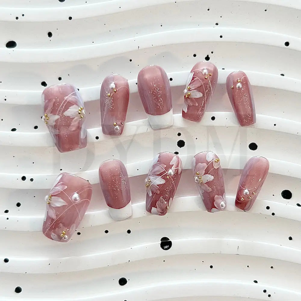 Blooming Fantasy Handmade press-on nails in pink, with classic French tip, white flowers, charming pearl accents, and glitters for an elegant and charming look.