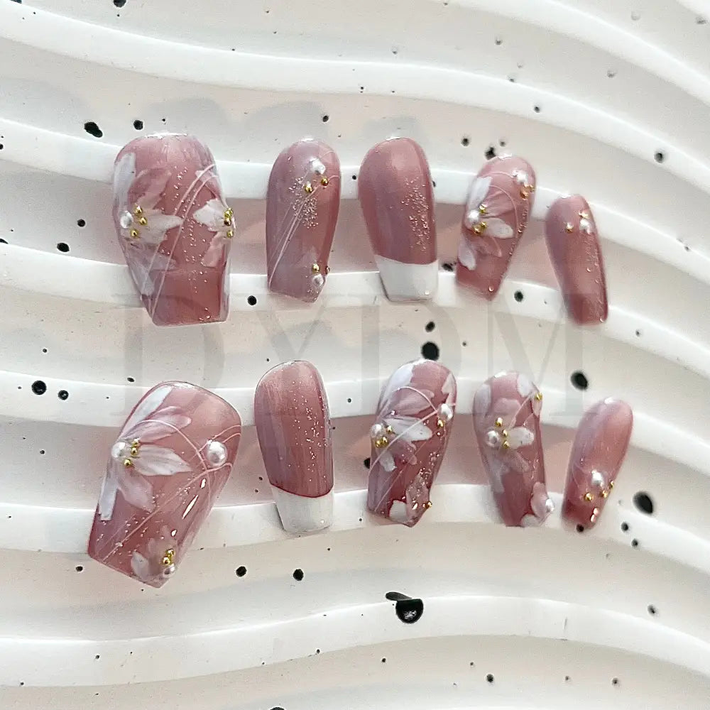 Blooming Fantasy Handmade press-on nails in pink, with classic French tip, white flowers, charming pearl accents, and glitters for an elegant and charming look.