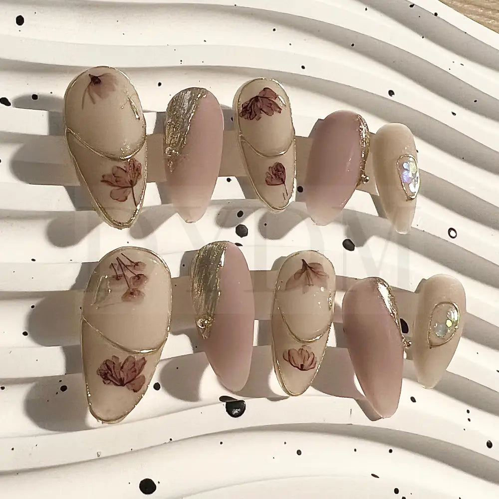 Blushing Petals Handmade, long almond-shaped press-on nails with a pink blush color, elegant flower and gold foil accents, combining delicate femininity with a touch of luxury