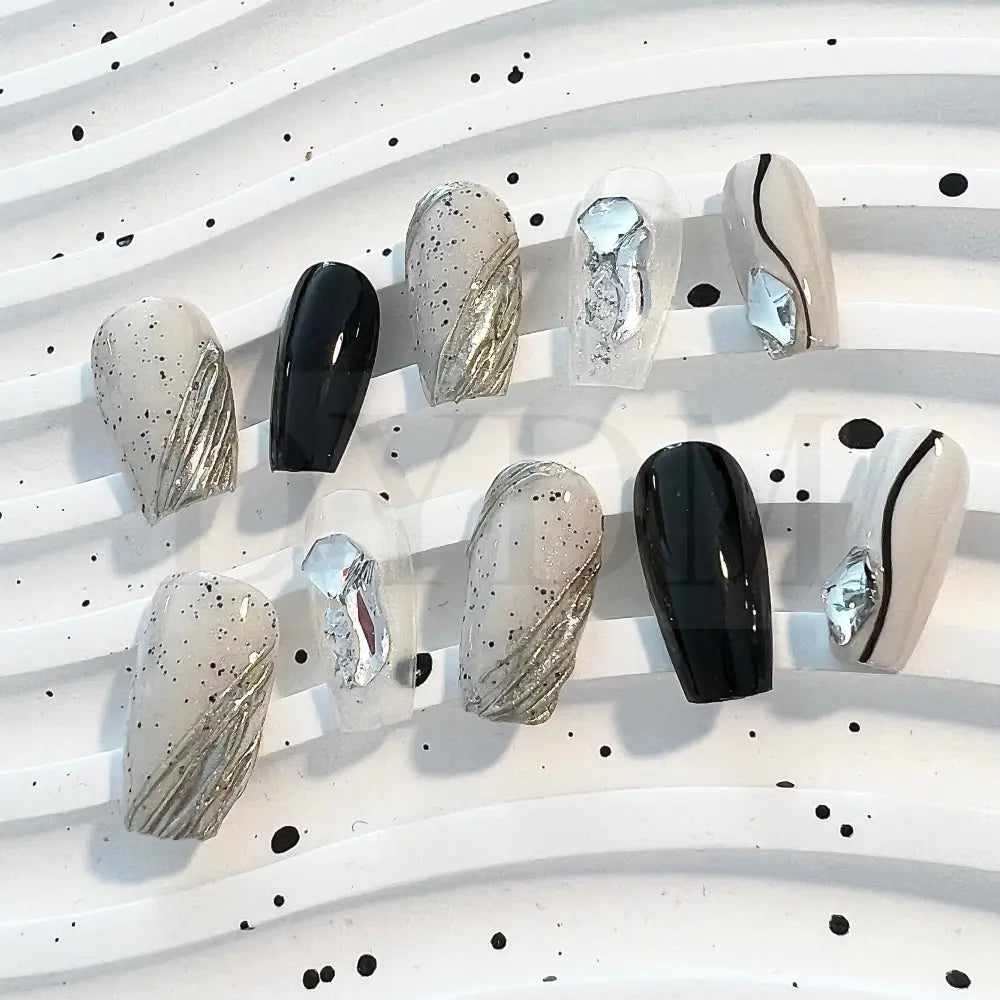 Eggshell Chic modern and sophisticated handmade press on nails that combines sleek black lines, playful black speckle dots, and sparkling gemstones