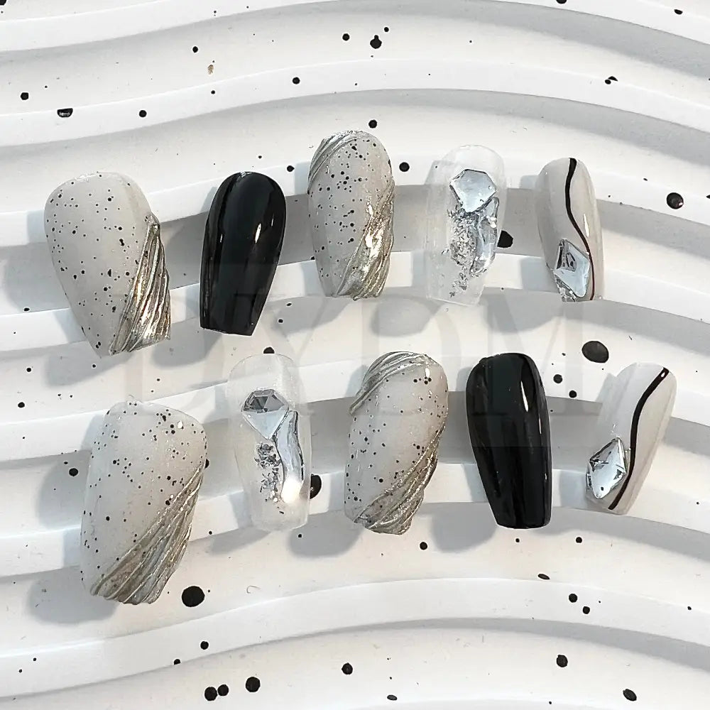 Eggshell Chic modern and sophisticated handmade press on nails that combines sleek black lines, playful black speckle dots, and sparkling gemstones