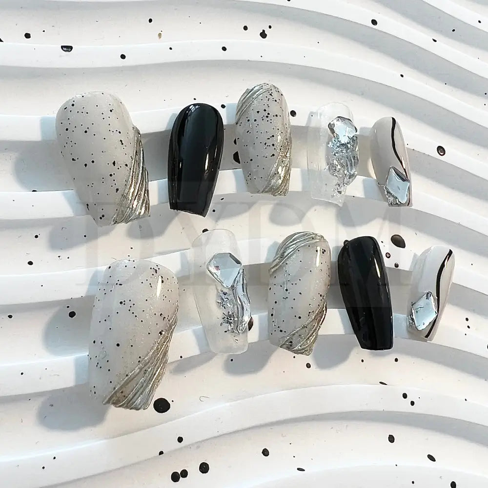 Eggshell Chic modern and sophisticated handmade press on nails that combines sleek black lines, playful black speckle dots, and sparkling gemstones