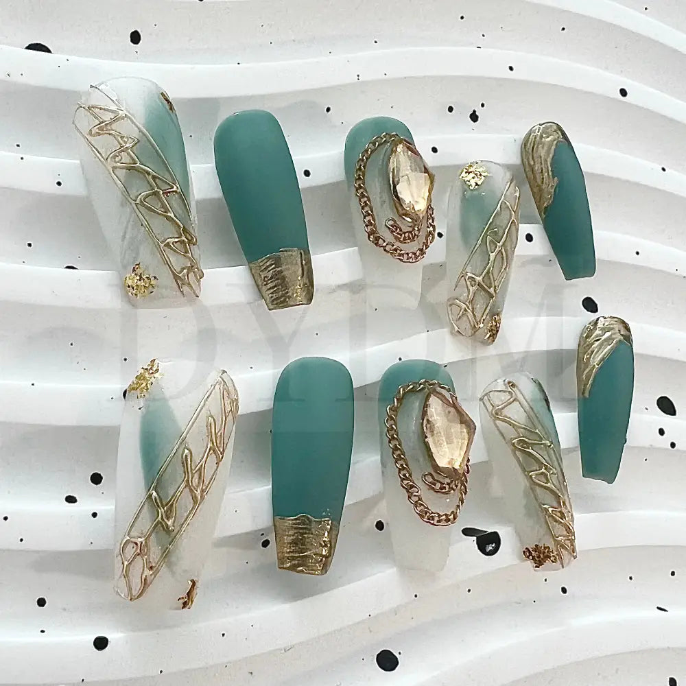 French Rococo Featuring an aqua base, these handmade press-on nails are adorned with golden embellishments, including a golden tip and a sparkling gemstone, for a truly extravagant and luxurious look.