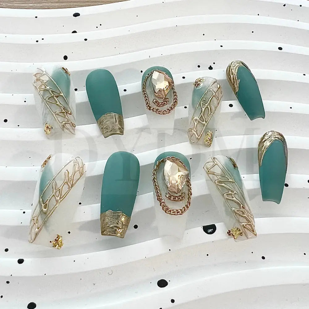 French Rococo Featuring an aqua base, these handmade press-on nails are adorned with golden embellishments, including a golden tip and a sparkling gemstone, for a truly extravagant and luxurious look.