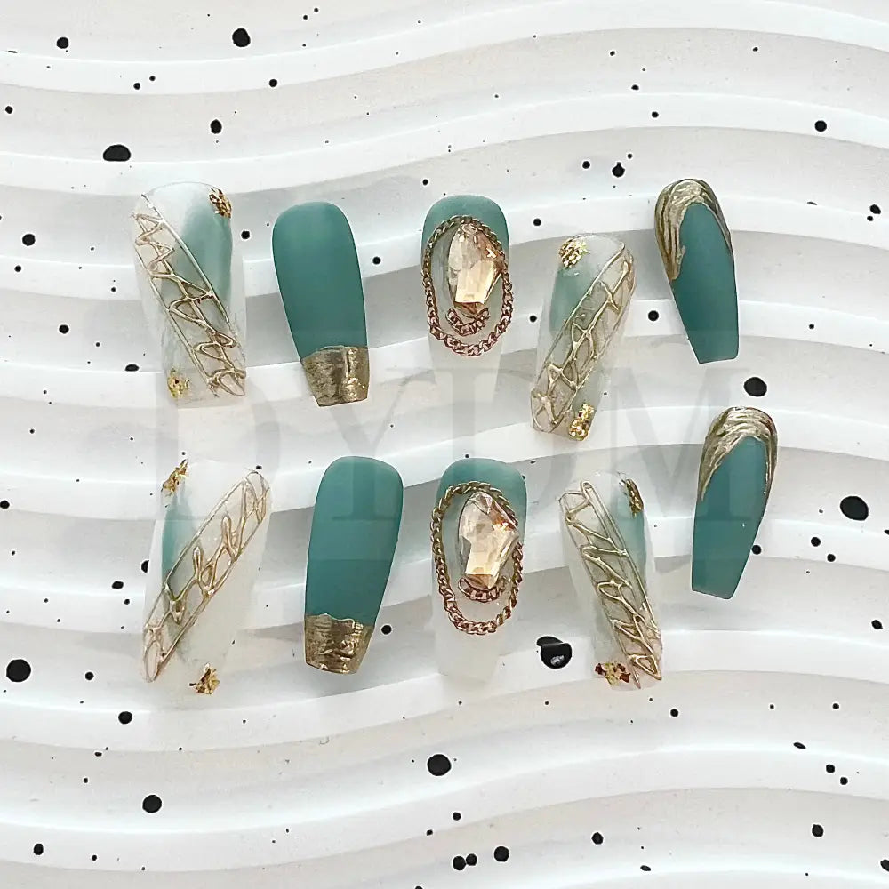 French Rococo Featuring an aqua base, these handmade press-on nails are adorned with golden embellishments, including a golden tip and a sparkling gemstone, for a truly extravagant and luxurious look.