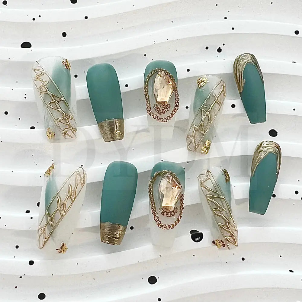 French Rococo Featuring an aqua base, these handmade press-on nails are adorned with golden embellishments, including a golden tip and a sparkling gemstone, for a truly extravagant and luxurious look.