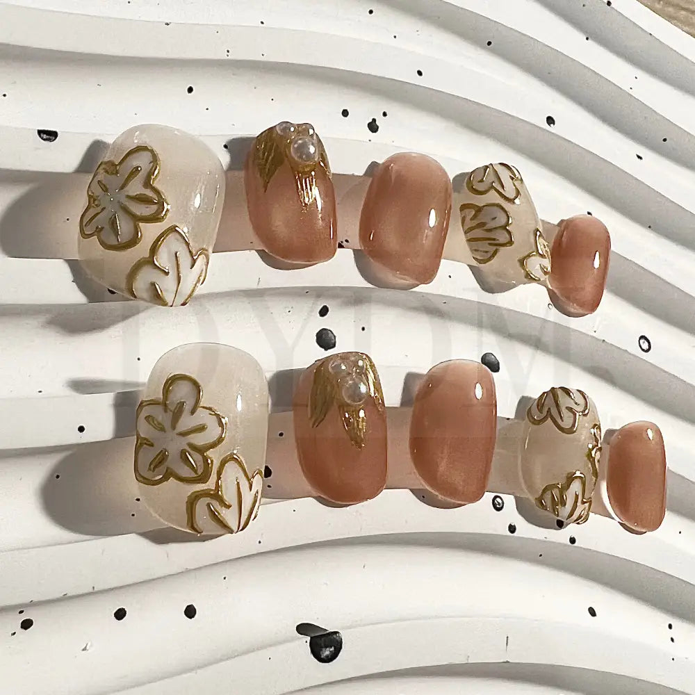 Golden Petals short round handmade press-on nails feature golden flower details and delicate pearl embellishment. 