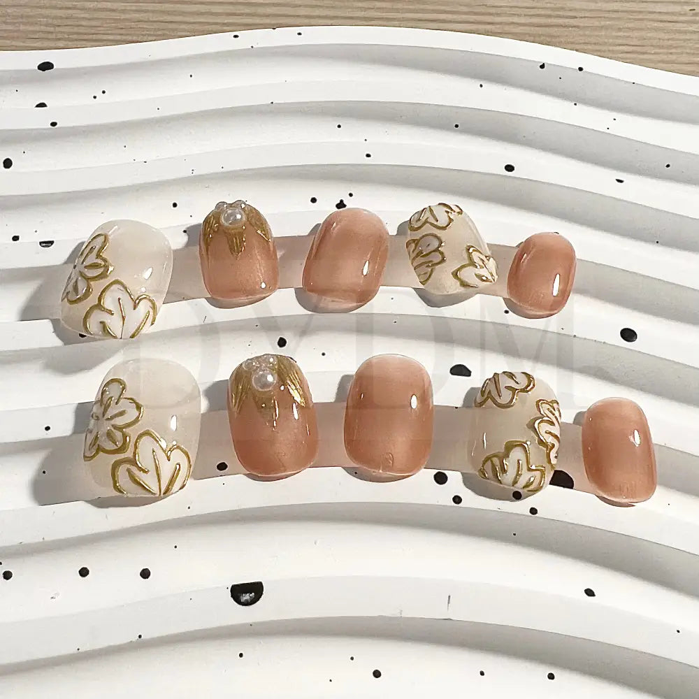 Golden Petals short round handmade press-on nails feature golden flower details and delicate pearl embellishment. 