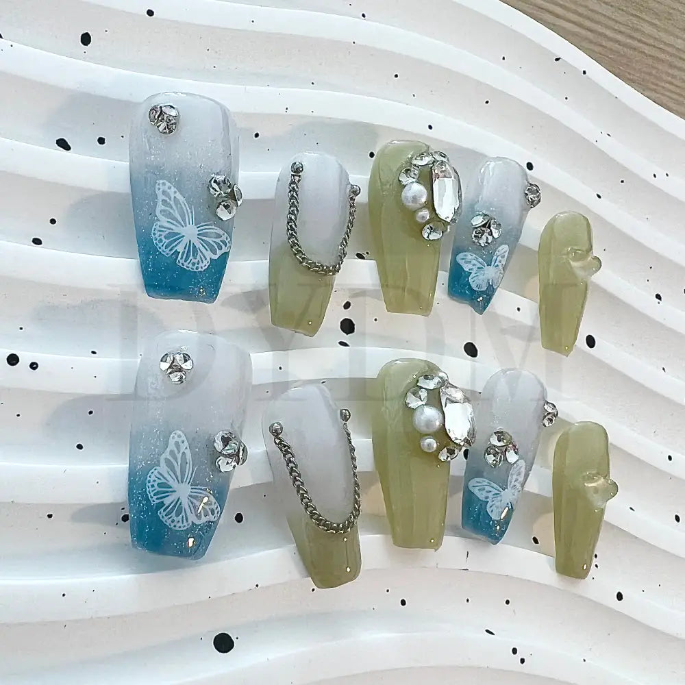 Gradient Chain Jewels Elevate your look with our elegant press-on nails featuring a blue and green gradient effect, adorned with shimmering gemstones and delicate butterfly designs for a touch of sophisticated beauty.