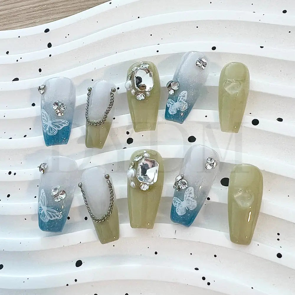 Gradient Chain Jewels Elevate your look with our elegant press-on nails featuring a blue and green gradient effect, adorned with shimmering gemstones and delicate butterfly designs for a touch of sophisticated beauty.